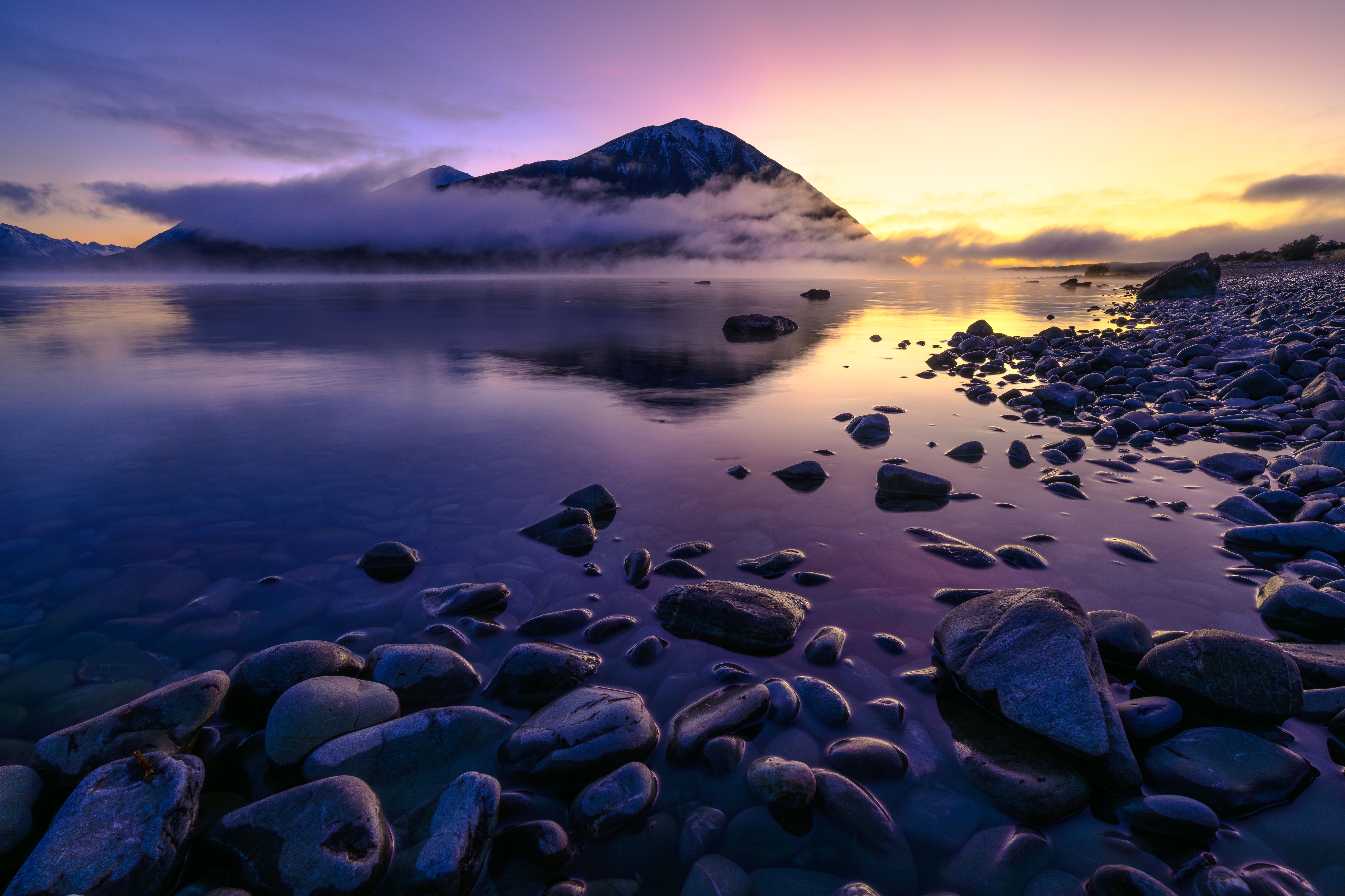 Dramatic sunrise sky with clearing clouds over a mountain lake